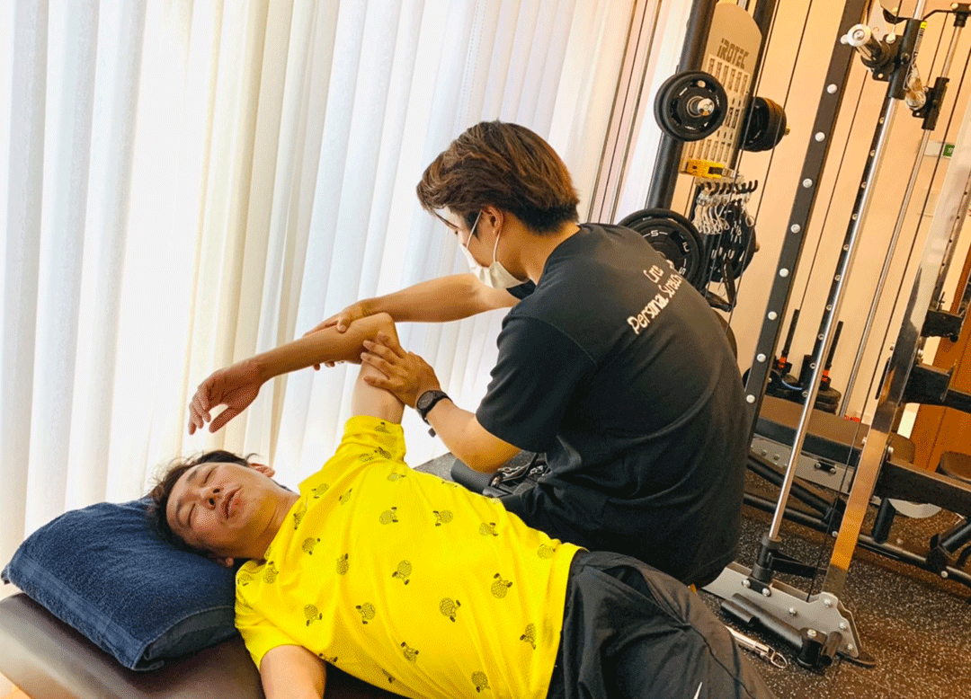 トレーナーが骨盤を押さえ姿勢を確認する様子