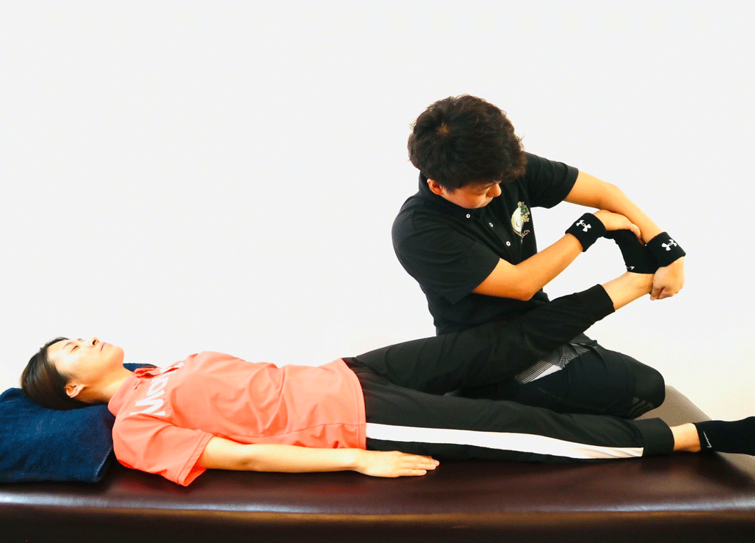 トレーナーが利用者の下肢を持ちストレッチする様子
